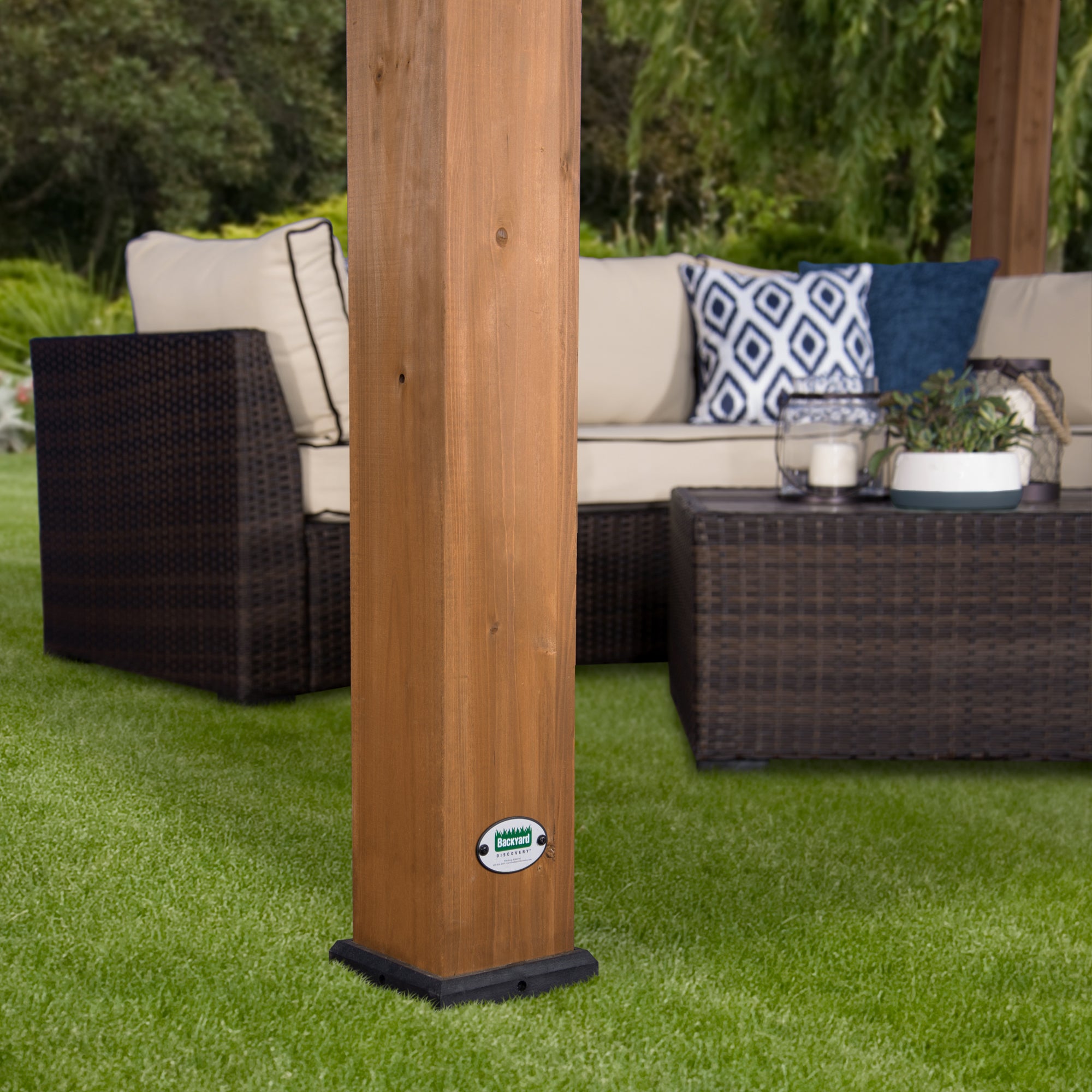 Outdoor pergola cedar post with black base on grass with patio furniture in background